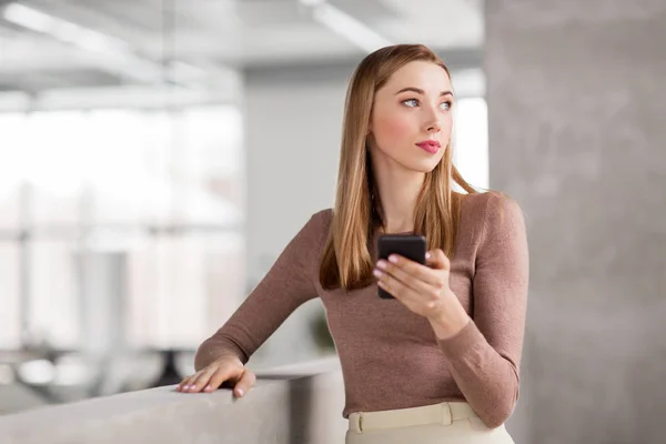 Mujer de negocios feliz con teléfono inteligente en la oficina —  Fotos de Stock