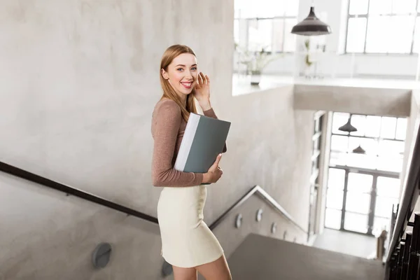 Mujer feliz con carpeta caminando abajo — Foto de Stock