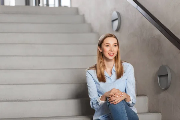 Счастливая улыбающаяся женщина или студент, сидящий на лестнице — стоковое фото