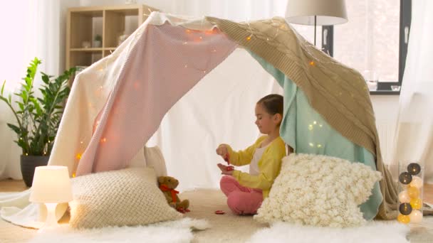 Счастливая девушка в детской палатке играет чаепитие дома — стоковое видео