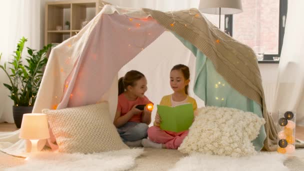 Niñas felices leyendo libro en tienda de campaña para niños en casa — Vídeos de Stock