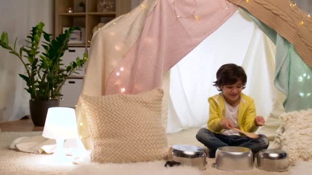 Junge mit Töpfen musiziert zu Hause im Kinderzelt — Stockvideo