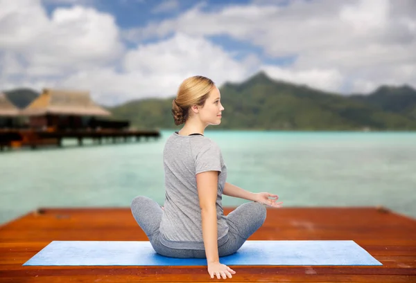 Жінка робить йогу в крученій позі на мат на відкритому повітрі — стокове фото