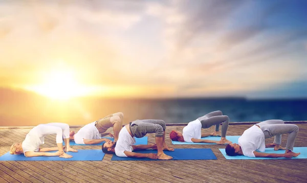 Groep mensen doen yoga brug pose buitenshuis — Stockfoto