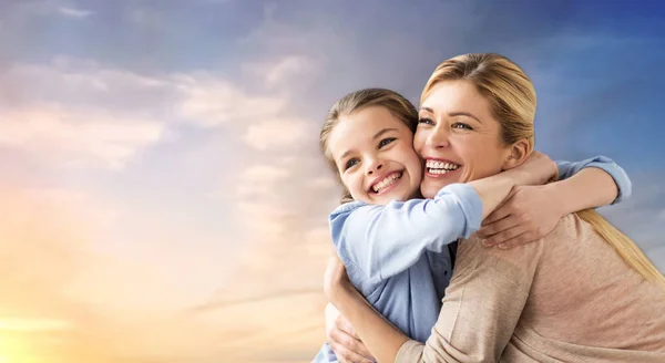 Счастливая улыбающаяся мать обнимает дочь по небу — стоковое фото