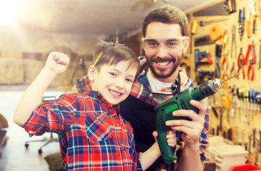 father and son with drill working at workshop clipart