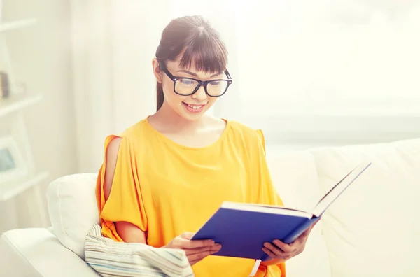 Sorridente giovane donna asiatica lettura libro a casa — Foto Stock