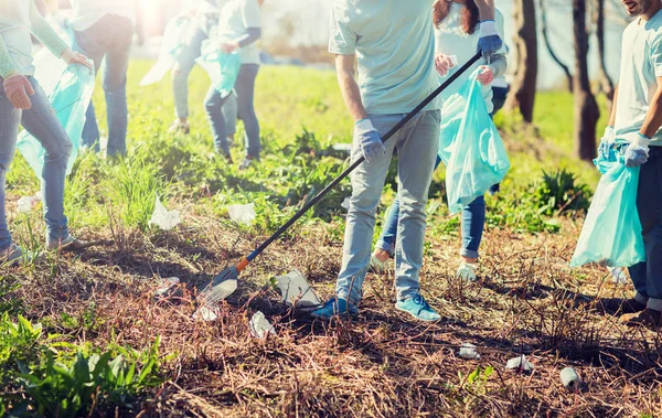 Relawan dengan kantong sampah membersihkan area taman — Stok Foto