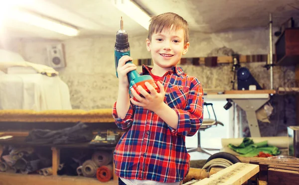 Glücklicher kleiner Junge mit Bohrer in der Werkstatt — Stockfoto