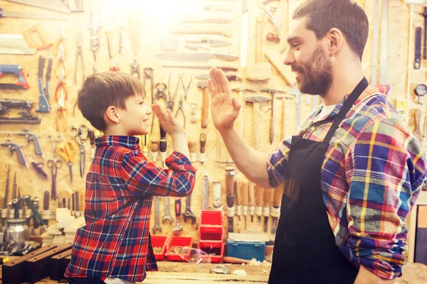 Отец и маленький сын дают пять в мастерской — стоковое фото