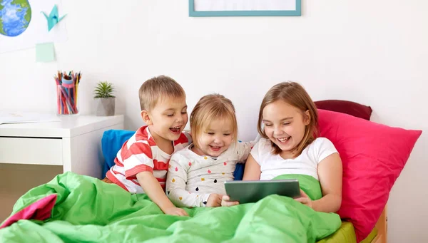 Маленькие дети с планшетным ПК в постели дома — стоковое фото
