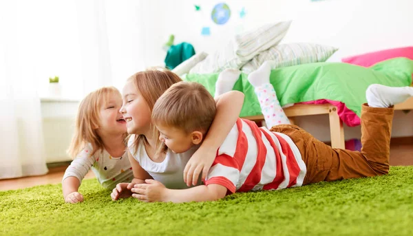 Niños pequeños y felices tumbados en el suelo o la alfombra — Foto de Stock