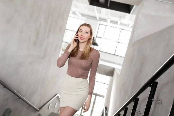 Businesswoman with smartphone walking upstairs — Stock Photo, Image