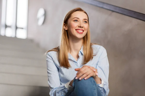 Mutlu gülümseyen kadın ya da merdivenlerde oturan öğrenci — Stok fotoğraf