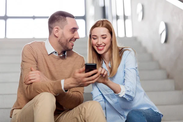 Man and woman with smartphone at office stairs — Stock Photo, Image