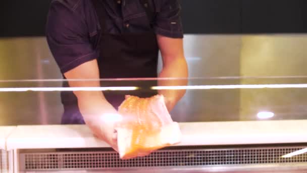 Продавец поставляет филе рыбы в холодильник в магазине — стоковое видео