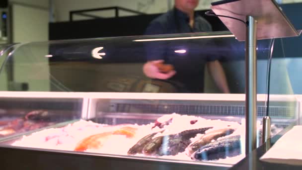 Продавец упаковывает рыбу в бумагу в магазине морепродуктов — стоковое видео