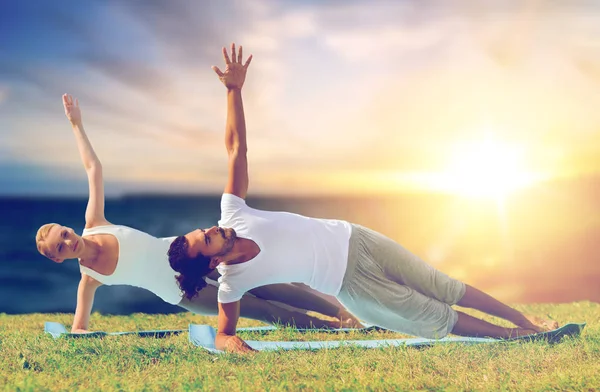Pareja haciendo yoga y tablón lateral al aire libre — Foto de Stock