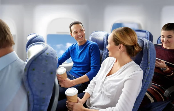 Happy passengers with coffee talking in plane — Stock Photo, Image