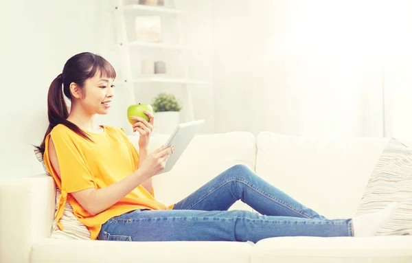 Szczęśliwa kobieta Azji z komputera typu tablet i jabłko w domu — Zdjęcie stockowe