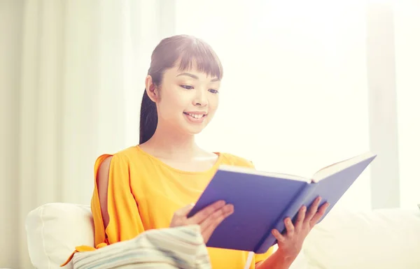 Sourire jeune asiatique femme lecture livre à la maison — Photo
