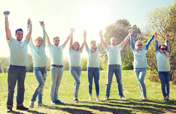 Groep gelukkig vrijwilligers buitenshuis hand in hand — Stockfoto