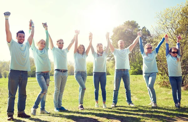 Groupe de bénévoles heureux tenant la main à l'extérieur — Photo