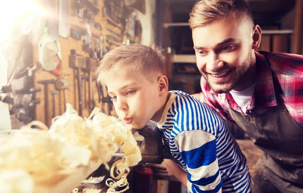 Padre e hijo pequeño con tablón de madera en el taller —  Fotos de Stock