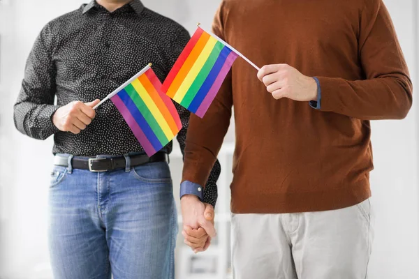 Manliga par med gay pride flaggor håller händerna — Stockfoto