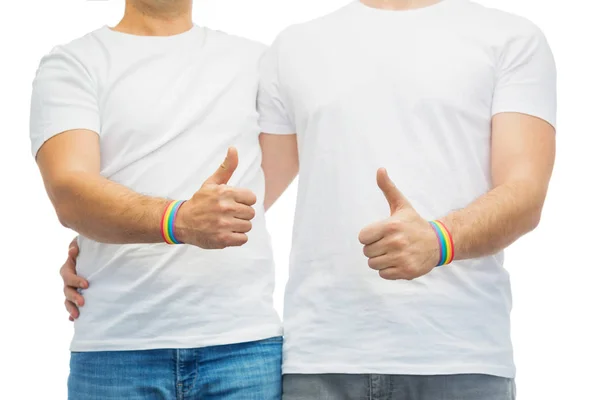 Homosexuella par med rainbow armband visar tummen upp — Stockfoto