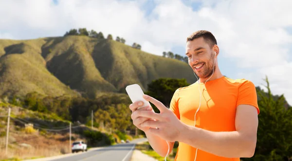 Man met smartphone en oortelefoons over heuvels — Stockfoto