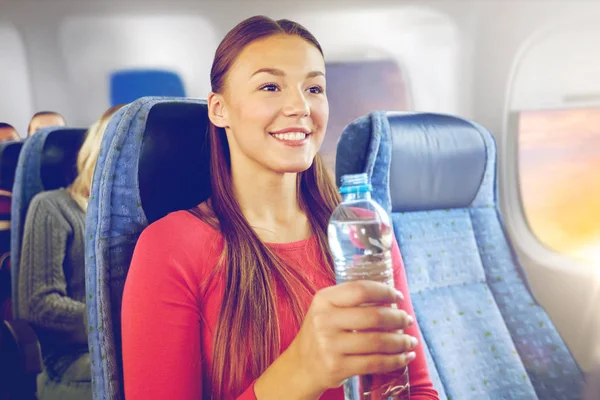 Glückliche junge Frau mit Wasserflasche im Flugzeug — Stockfoto