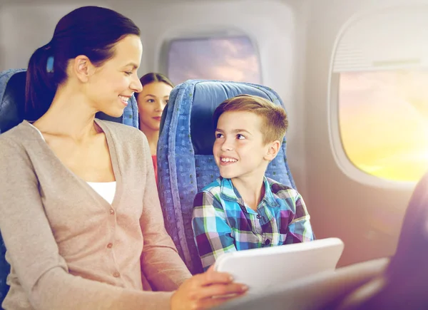 Familia feliz con la tableta PC sentado en el avión — Foto de Stock
