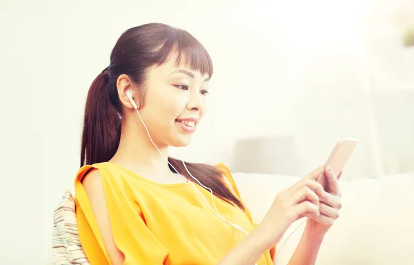 Счастливая азиатская женщина со смартфоном и наушниками — стоковое фото