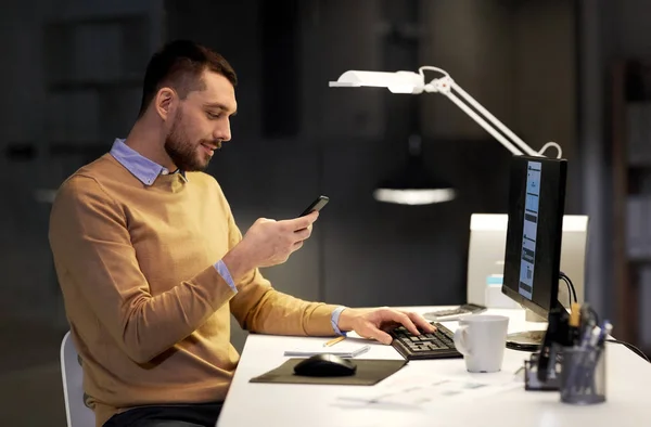 Mann mit Smartphone arbeitet spät nachts im Büro — Stockfoto
