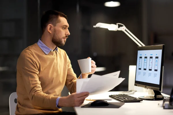 Человек с бумагами и компьютером работает в ночном офисе — стоковое фото