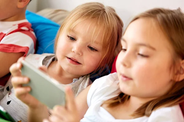 Små barn med smartphone i sängen hemma — Stockfoto