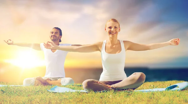 Gelukkige paar maken van yoga en mediteren buitenshuis — Stockfoto