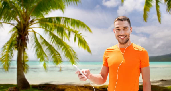 Uomo con smartphone e auricolari sulla spiaggia — Foto Stock