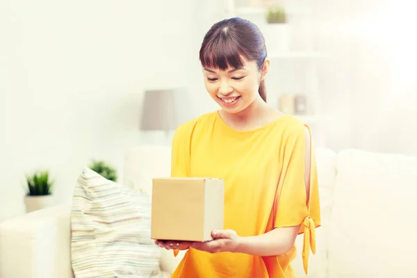 Happy asian young woman with parcel box at home — Stock Photo, Image