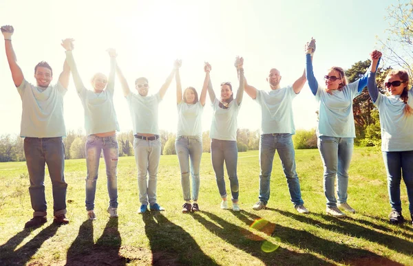 Groep gelukkig vrijwilligers buitenshuis hand in hand — Stockfoto