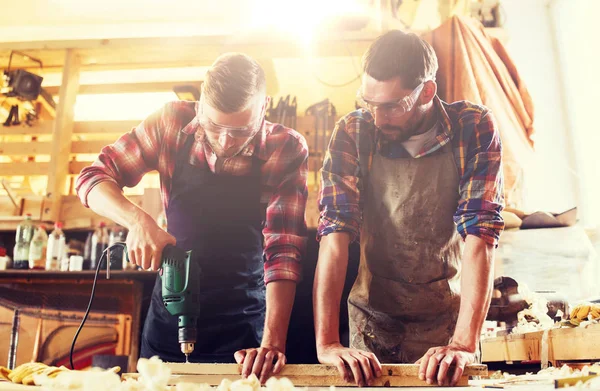 Carpenters with drill drilling plank at workshop — Stock Photo, Image