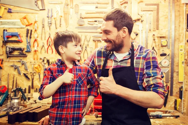 Отец и маленький сын делают большие пальцы в мастерской — стоковое фото