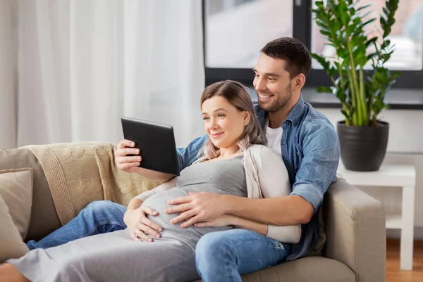 Tablet pc vasıl ev ile hamile kadın ve erkek — Stok fotoğraf