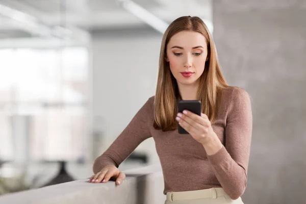 Happy businesswoman with smartphone at office — Stock Photo, Image