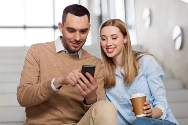 Мужчина и женщина со смартфоном на офисной лестнице — стоковое фото
