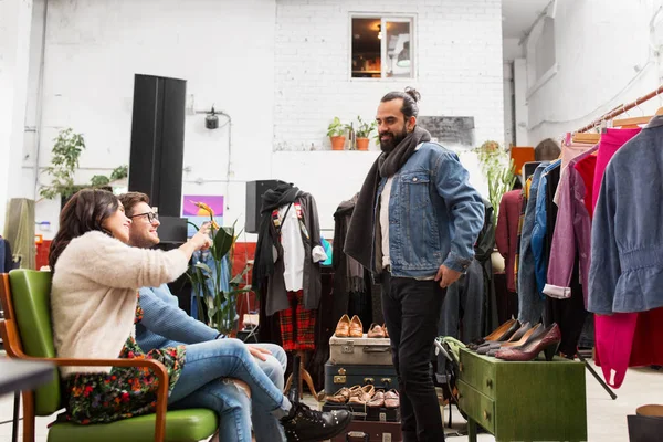Amigos eligiendo ropa en la tienda de ropa vintage —  Fotos de Stock