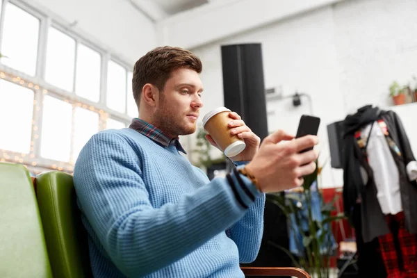 Homme avec smartphone et café au magasin de vêtements — Photo