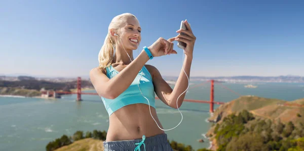 Mulher com smartphone e fones de ouvido fazendo esportes — Fotografia de Stock