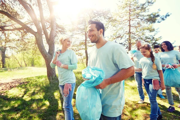 Voluntários com sacos de lixo andando ao ar livre — Fotografia de Stock